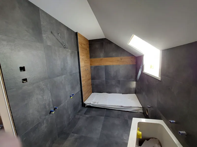 Salle de bains carrelée en grès cérame anthracite avec niche en bois, réalisation GPN Sàrl