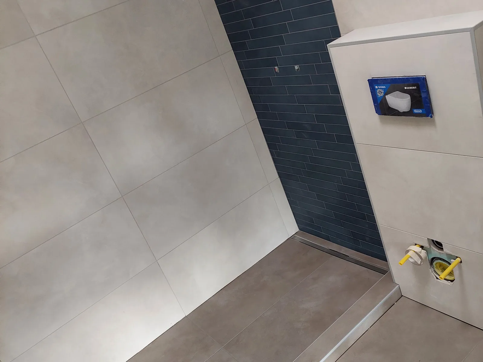 Douche à l'italienne : mur d'accent en faïence bleu nuit pose décalée, grands formats beige, caniveau inox