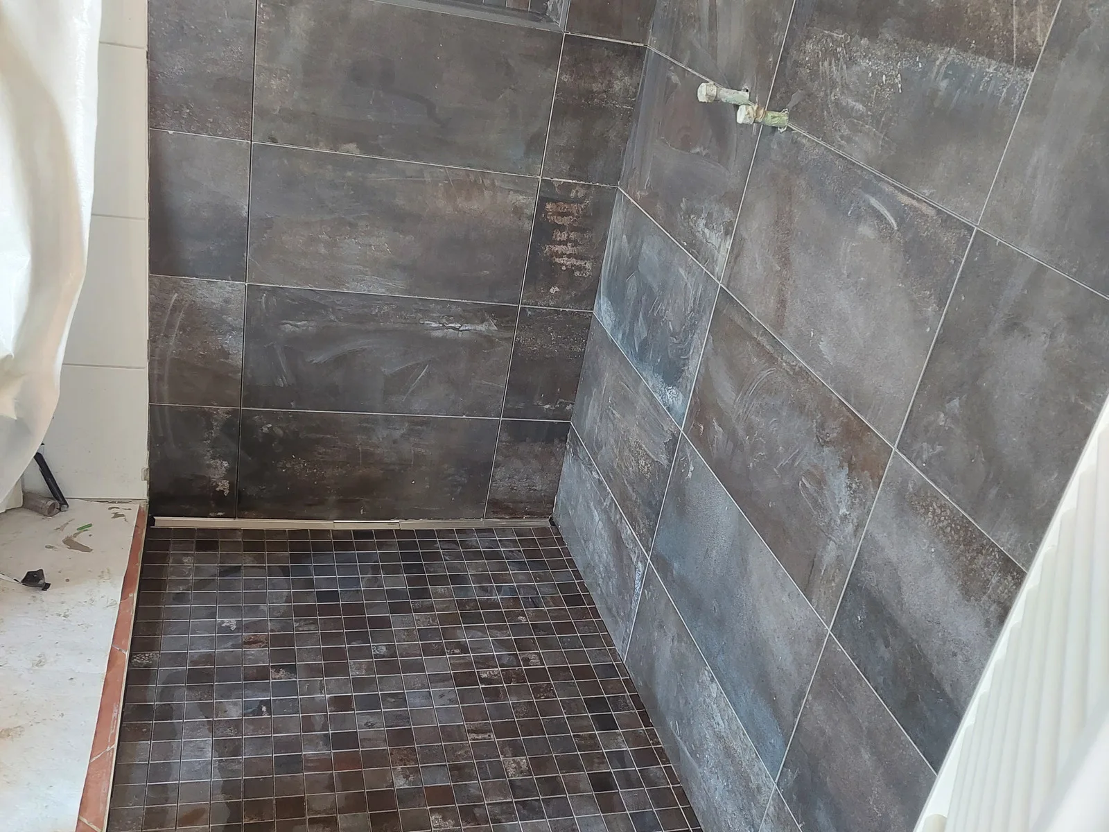 Receveur de douche en mosaïque brune, murs grès cérame effet métal oxydé, caniveau de douche affleurant